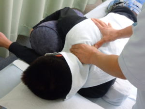 横向きで首から肩への指圧マッサージを受ける男性の画像